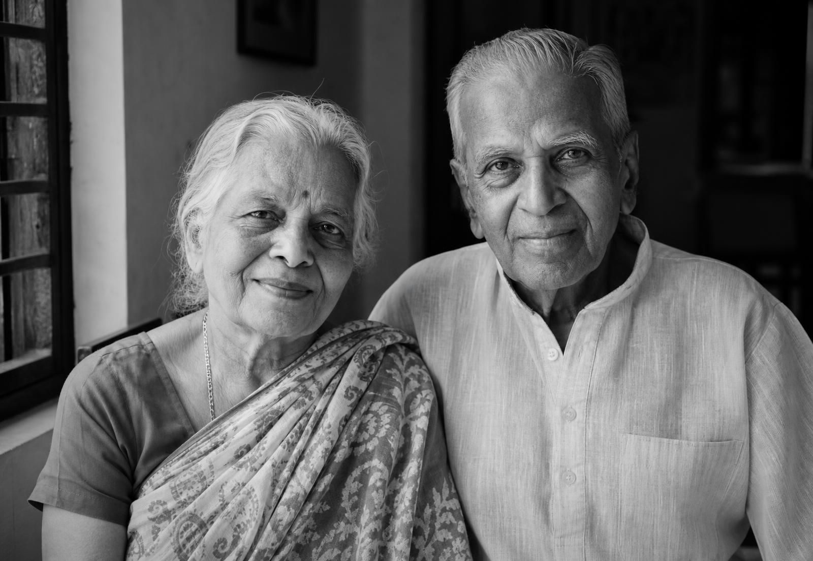 Black and white portrait of an older Indian couple sitting together by a window